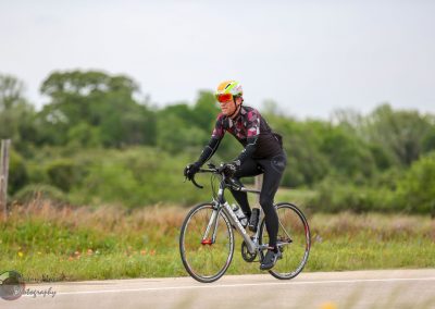 Vibrant cyclist riding on scenic countryside road in Bluebonnet Express event.