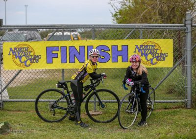 1. Female cyclists at finish line of North West Cycling Club event, smiling after completing ride.