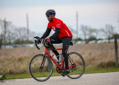 Cyclist riding a road bike on a trail during daytime with nature scenery.