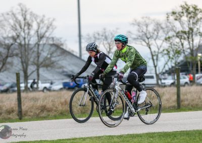 Cyclists riding on a paved trail during daytime in a scenic outdoor setting.
