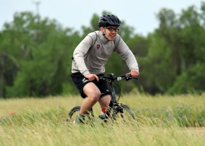 Young man cycling through a grassy field on a mountain bike in outdoor adventure.