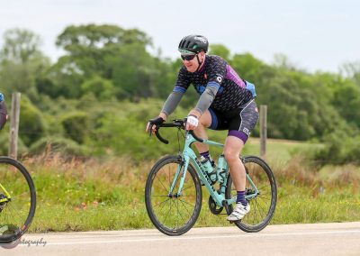Bright cyclist riding a Bianchi gravel bike on roadside trail.