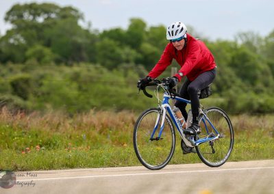 Smooth road cyclist pedaling on outdoor path in nature with Bluebonnet Express branding.