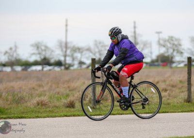 Comfortable cyclist riding a bike outdoors on a paved path, wearing helmet and sporty attire.