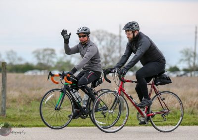 Two cyclists riding on a paved trail, enjoying outdoor biking adventure.