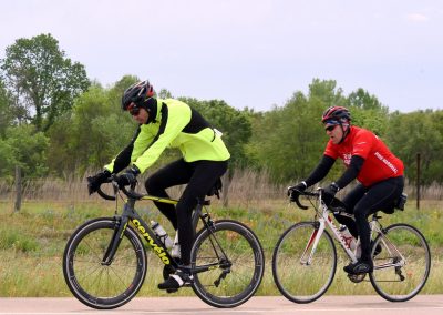 Bright yellow and red cyclists riding on a scenic bike trail in Texas during daytime.