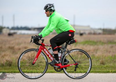 Vibrant cyclist riding a red and black Cervélo bike in an open field, showcasing Bluebonnet Express cycling adventures.