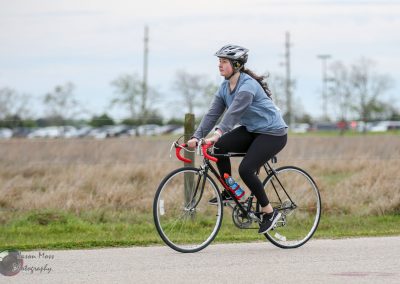 Comfortable woman riding a bike during daytime outdoors in casual athletic wear.