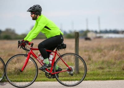 Bright green cycling jacket and red bike on scenic outdoor trail for Bluebonnet Express.
