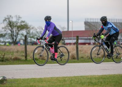 Brightly dressed cyclists riding bikes outdoors during daytime, emphasizing Bluebonnet Express cycling event or ride.