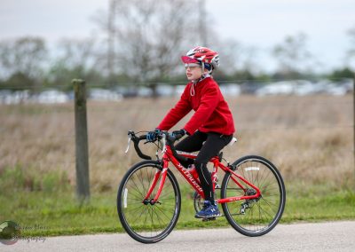 Bright young cyclist riding a red Specialized bike in outdoor park, wearing a helmet and red jacket for safety and fun.