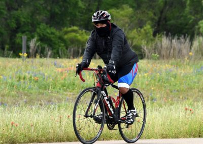 Vegan male cyclist riding a road bike through a scenic green field with wildflowers.