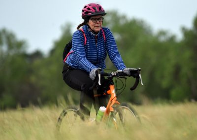 Women riding a mountain bike on a trail in nature, promoting outdoor cycling with Bluebonnet Express.