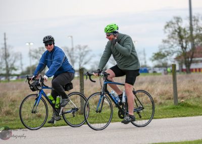 Cyclists riding on a scenic bike trail in Texas with Bluebonnet Express branding.
