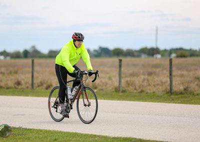 Bright yellow cycling jacket for Bluebonnet Express bike tour, outdoor biking adventure in open fields.