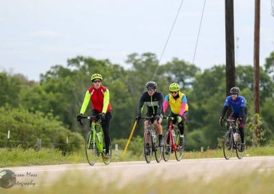 Bright cycling group riding on scenic rural road in vibrant sportswear for Bluebonnet Express race.