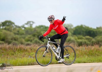Vibrant cyclist riding on scenic outdoor trail with lush greenery.