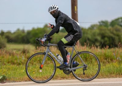 Velo cyclist in black sportswear and helmet riding on scenic countryside trail for fitness and adventure.