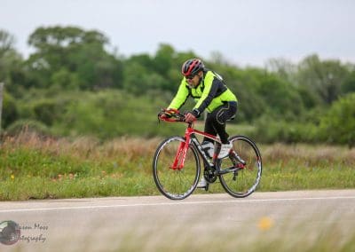 Bright yellow cycling jacket on male cyclist riding a road bike on a rural highway.