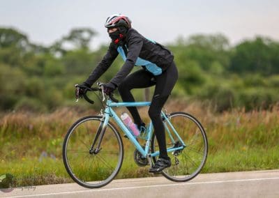 Bright blue bicycle on a scenic outdoor trail with a cyclist wearing protective gear, promoting eco-friendly transportation.