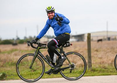 Vibrant cyclist riding a black and yellow bike outdoors in a rural setting.
