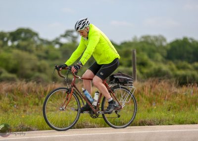 Vibrant cyclist riding along scenic rural road, promoting Bluebonnet Express bike routes.