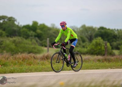 Bright green bike jersey with pink helmet on iconic Bluebonnet Express cycling route.