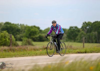 Vintage cyclist riding a road bike on scenic countryside trail during daytime.