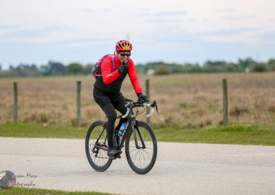 Bright female cyclist enjoying a ride on a scenic bike trail with open fields.