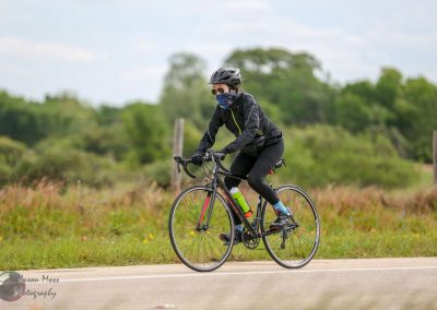Vibrant cyclist riding through scenic Texas countryside on Bluebonnet Express bike route.