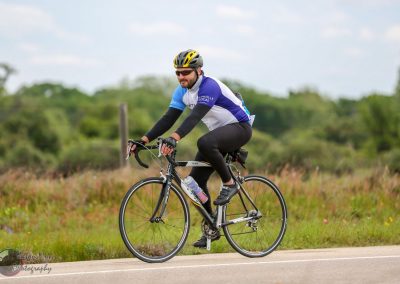 Bright male cyclist riding a road bike outdoors during a bicycle event, showcasing cycling gear and scenic landscape.