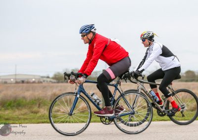 Bike Riders Cycling on Road with Open Fields in Background for Bluebonnet Express.