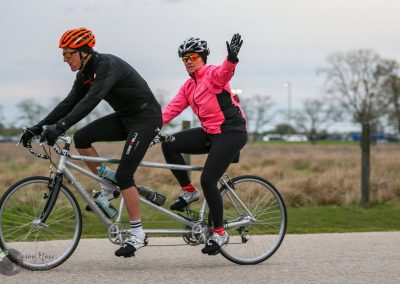 Two cyclists riding a tandem bike during daytime, showcasing outdoor cycling activities.