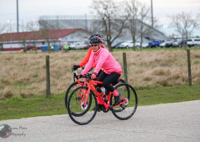 Bright pink and orange bikes riding through open park during daylight.