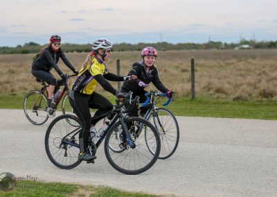 Bright outdoor cycling scene with women and a young girl riding bikes on a scenic trail, promoting family-friendly bike adventures.