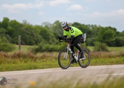 High-performance cycling athlete riding a road bike on scenic rural route for Bluebonnet Express event.