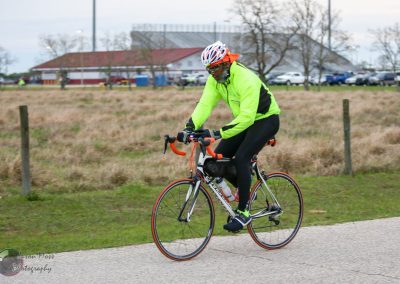 Vibrant cyclist wearing neon jacket riding Bluebonnet Express bike trail in Texas outdoor setting.