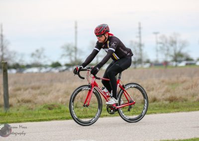 High-performance cyclist riding a red road bike outdoors during daytime.