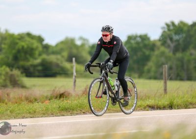 High-performance cyclist riding on a rural road, promoting Bluebonnet Express bike delivery service.
