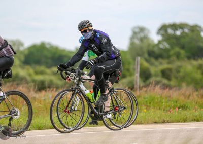 Cyclist in black gear riding on scenic country road during Bluebonnet Express event.