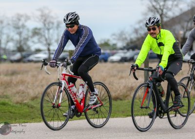 Brightly dressed cyclists riding electric bikes in a park during daytime, promoting eco-friendly transportation and outdoor activity.