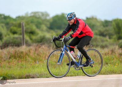 Vibrant cyclist riding a bike on scenic outdoor trail - Bluebonnet Express promotional image.