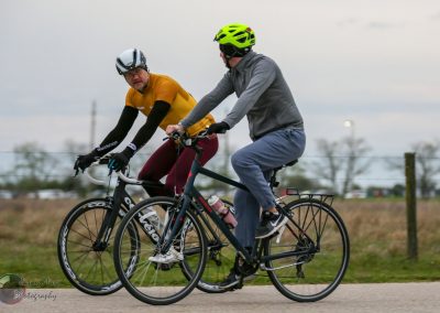 Cyclists riding electric bikes outdoors with scenic background for Bluebonnet Express promotion.