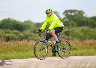 High-visibility cyclist riding along scenic outdoor route, promoting Bluebonnet Express bike services.