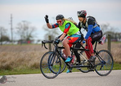 Vibrant cycling event featuring a woman and man riding tandem bicycles during Bluebonnet Express race.