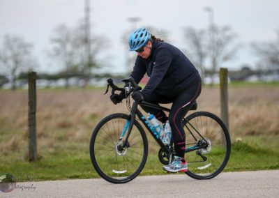 Vegan woman cycling outdoors on a black and blue bike during daytime, promoting active lifestyle.