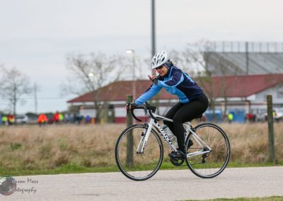Bright woman cyclist enjoying outdoor ride on a white road bike during daytime.