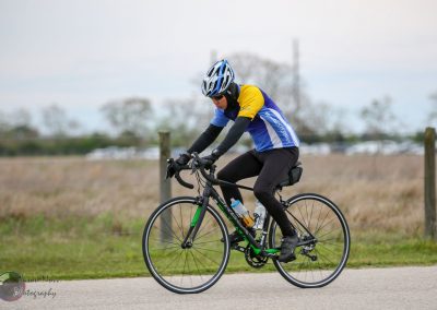 High-performance cyclist riding a road bike during daytime outdoor ride, promoting Bluebonnet Express services.