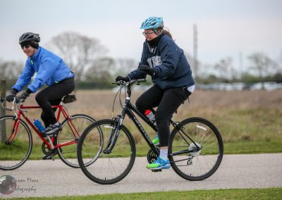 Comfortable women riding bicycles outdoors on a cloudy day for fitness and recreation.