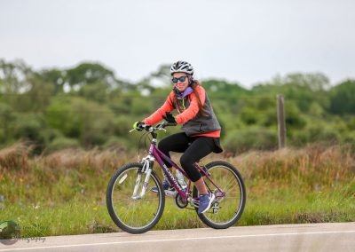 Vibrant woman cycling outdoors, promoting Bluebonnet Express bike rides and eco-friendly transport.